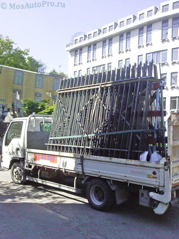 Перевозка секций металлического забора на машине с пирамидой в центре Москвы.