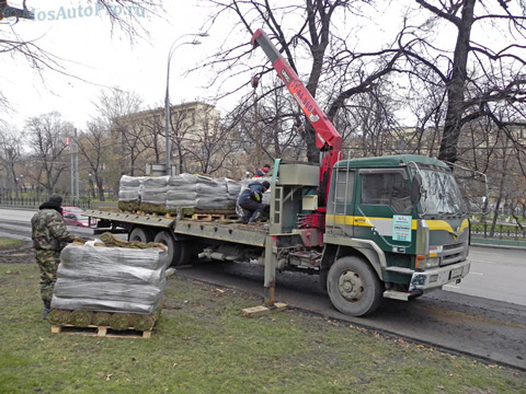 Разгрузка газонов на поддонах манипулятором в центре Москвы.